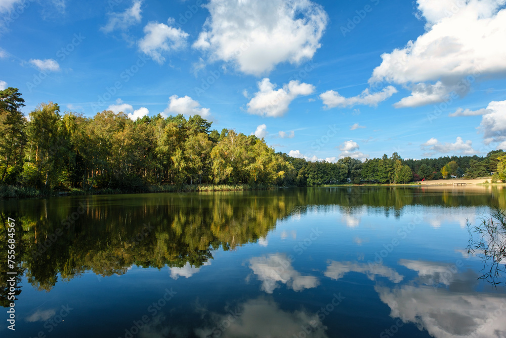 Natural landscape of the lake, high definition, the movement of waves against the background of the autumn forest. The reflection of clouds on the ripples of water. Germany.