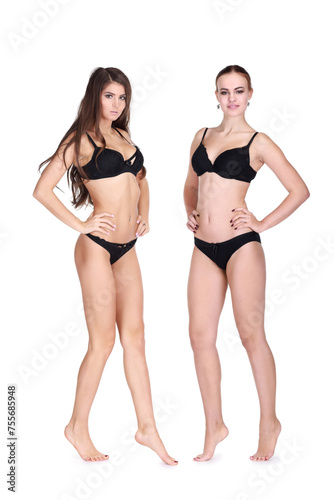 Two young women in black underwear pose isolated on white background