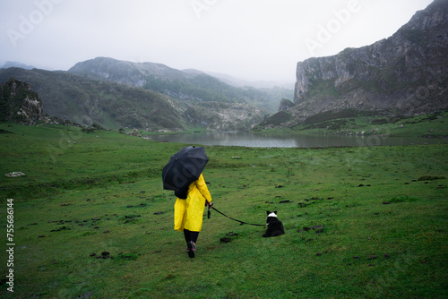 Rear view of an unrecognizable woman with her dog looking at lake Ercina in the Covadonga Lakes.