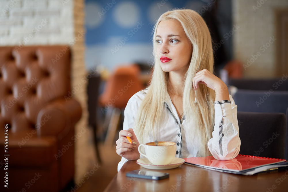 Young blonde business woman sits at table in cafe Young blonde business woman sits at table in cafe
