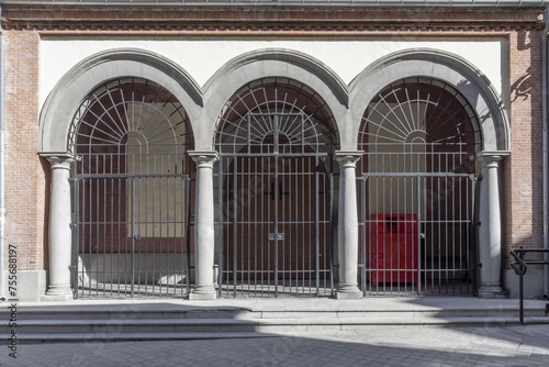 Facade of a church with semicircular arches with black metal bars