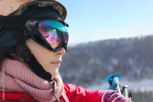 Girl in ski goggles looks away during lifting at cableway in ski resort at winter day photo