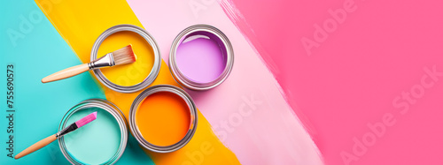 Banner with four open cans of paint with brushes on them on bright colorful background. Yellow, orange, pink, blue colors of paint. Top view, copy space. House renovation web line sale, special offer photo