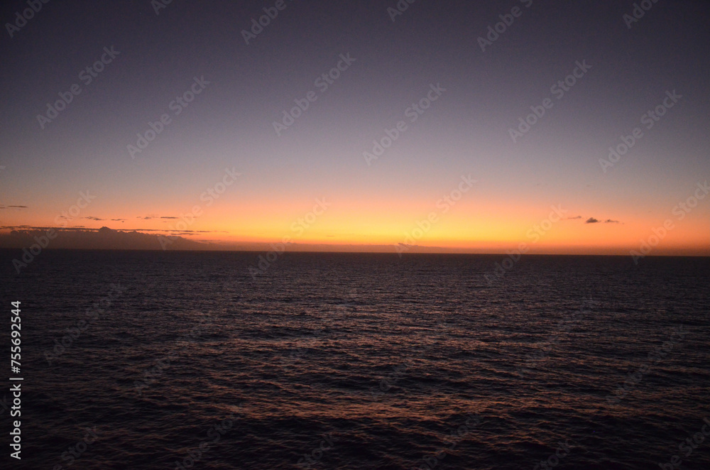 Sunset at sea, reflections of sun rays on rippled water surface, clear sky, concept for traveling and tourism