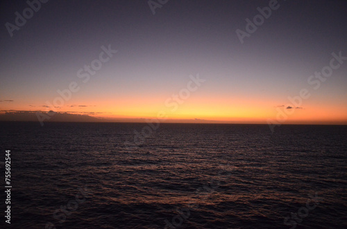Sunset at sea, reflections of sun rays on rippled water surface, clear sky, concept for traveling and tourism