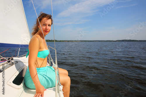 Pretty woman sits on yacht during sailing on river at sunny summer day © Pavel Losevsky