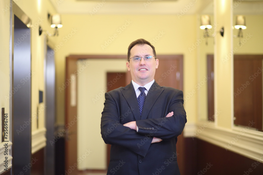 Handsome man standing with his arms crossed in the hallway between the elevator and mirrors