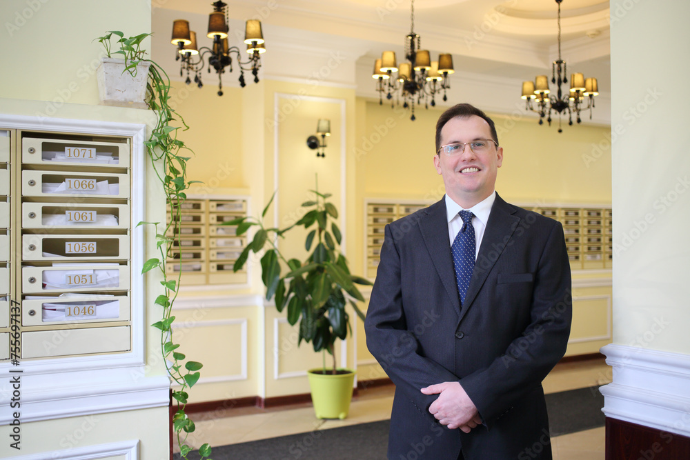 Handsome man in a business suit and tie standing in the hallway of the luxury apartment building Handsome man in a business suit and tie standing in the hallway of the luxury apartment building