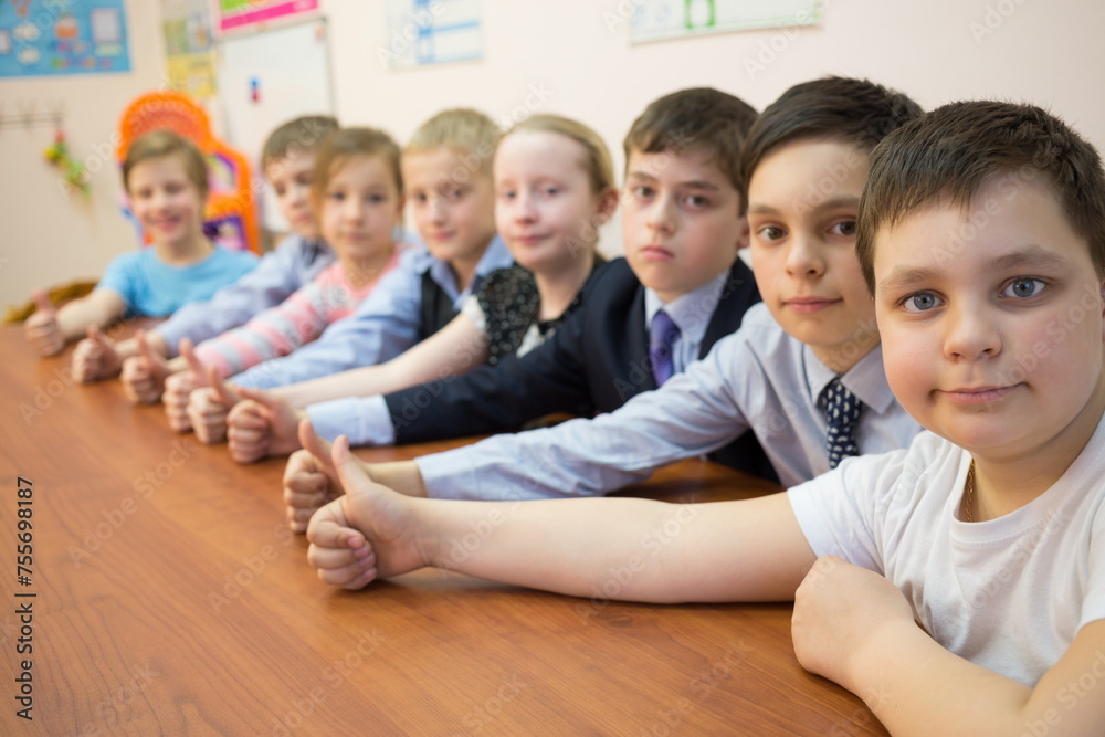 Eight children are thumbs-up and sitting at the table