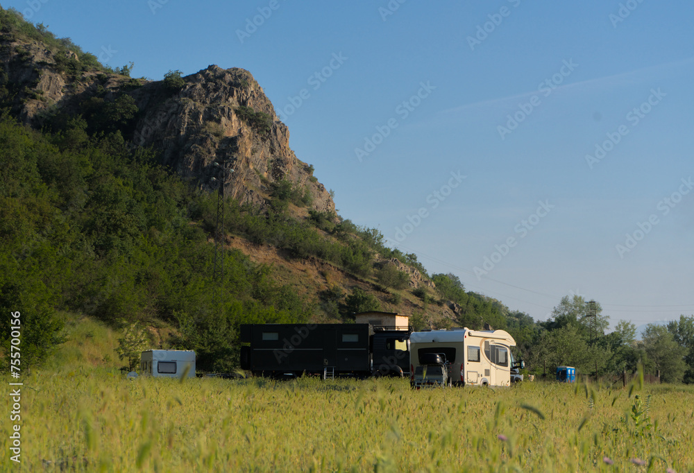 A camper park with campers at the foot of the mountains, steam rising from hot mineral springs visible. Bulgaria, Rupite