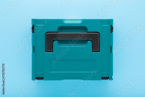 New dark black green professional plastic toolbox for repair tools, equipment or other things on light blue table background. Pastel color. Closeup. Top down view.