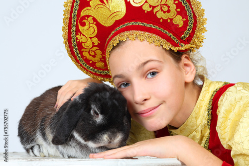 Pretty girl in red russian folk costume poses with rabit in white studio photo