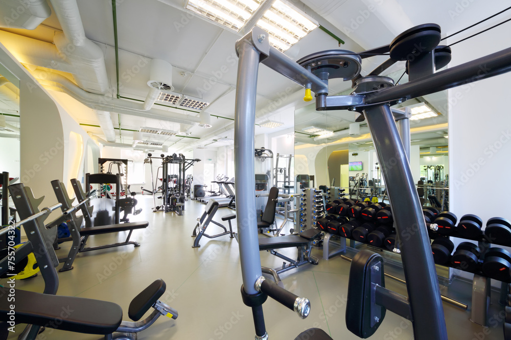 Modern gym with new shiny fitness equipment, big mirror for sport training