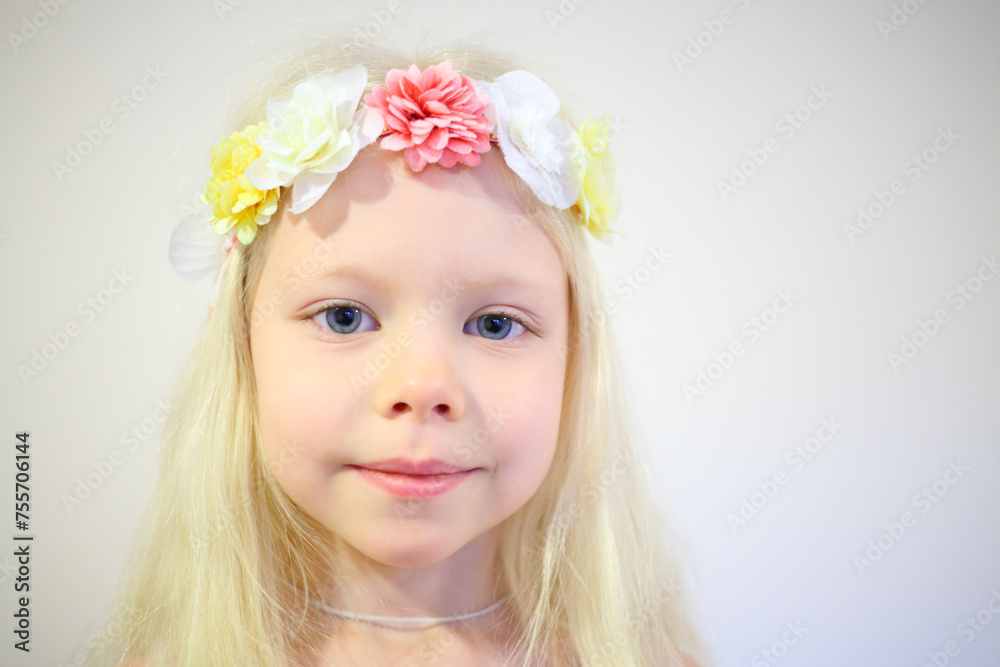 Little pretty blonde girl in wreath smiles in room with white wall Little pretty blonde girl in wreath smiles in room with white wall