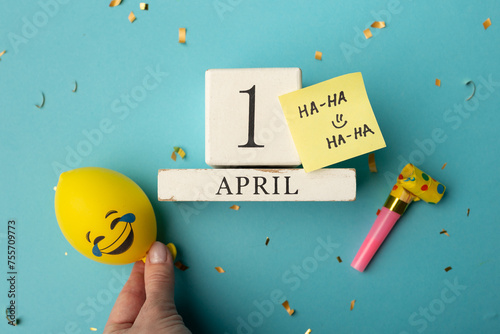 April 1st. Image of april 1 wooden calendar and festive decor on the blue background. April Fool's Day