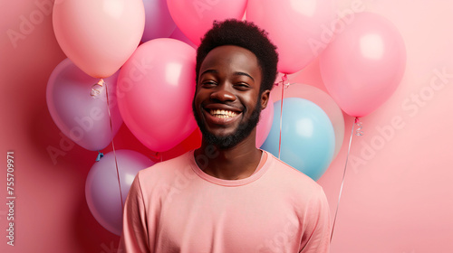 Joyful man with bright smile, balloons on pink background, conveying happiness and celebration. photo
