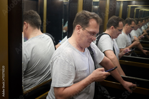 Foto Man with smartphone in elevator cab, recursive view