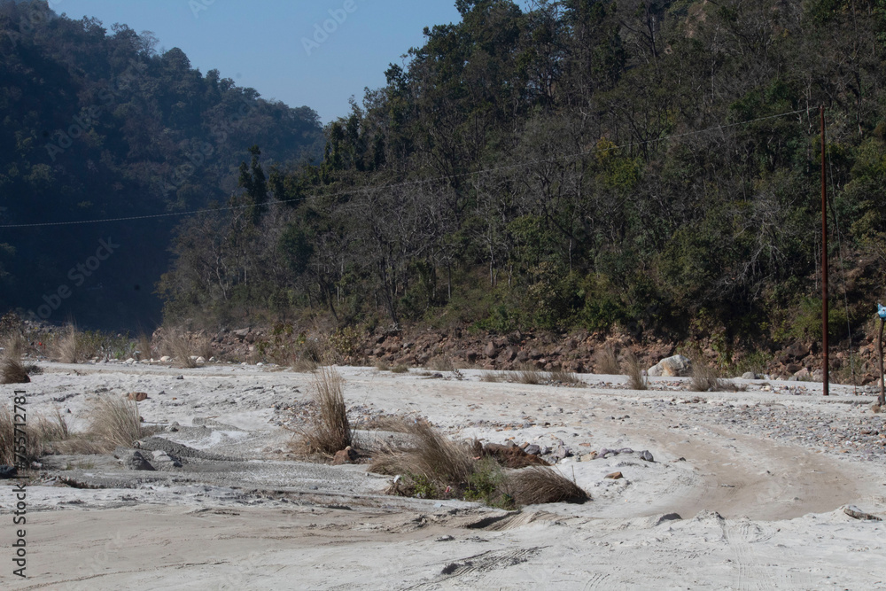 White sand beach framed by lush greenery. Rishikesh, nestled along the Ganges River in India, captivates with its serene ambiance. A harmonious blend of nature and spirituality, Uttarakhand