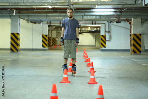 Roller skater stands near orange cones in empty underground parking