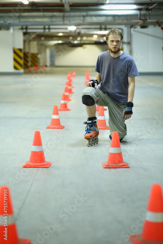 Roller skater poses on floor near orange cones in empty underground parking
