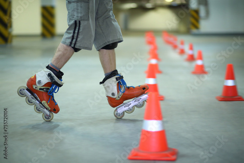 Legs of roller skater posing on floor near orange cones in indoor parking photo