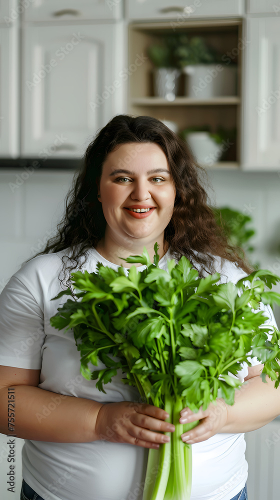Smiling fat woman with fresh bunch of greens, celery in a home kitchen. Healthy eating and wellness concept. Design for culinary website, dietitian blog, and healthy food program promotion Smiling fat woman with fresh bunch of greens, celery in a home kitchen. Healthy eating and wellness concept. Design for culinary website, dietitian blog, and healthy food program promotion