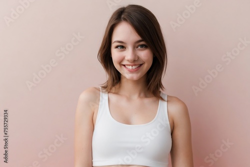 Happy young American woman wearing a white cropped tank top on a pink background with copy space.