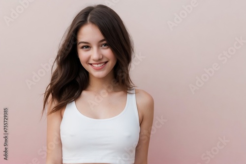 Happy young American woman wearing a white cropped tank top on a pink background with copy space.