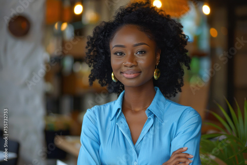 Afro businesswoman in blue formal shirt, arms crossed in meeting room