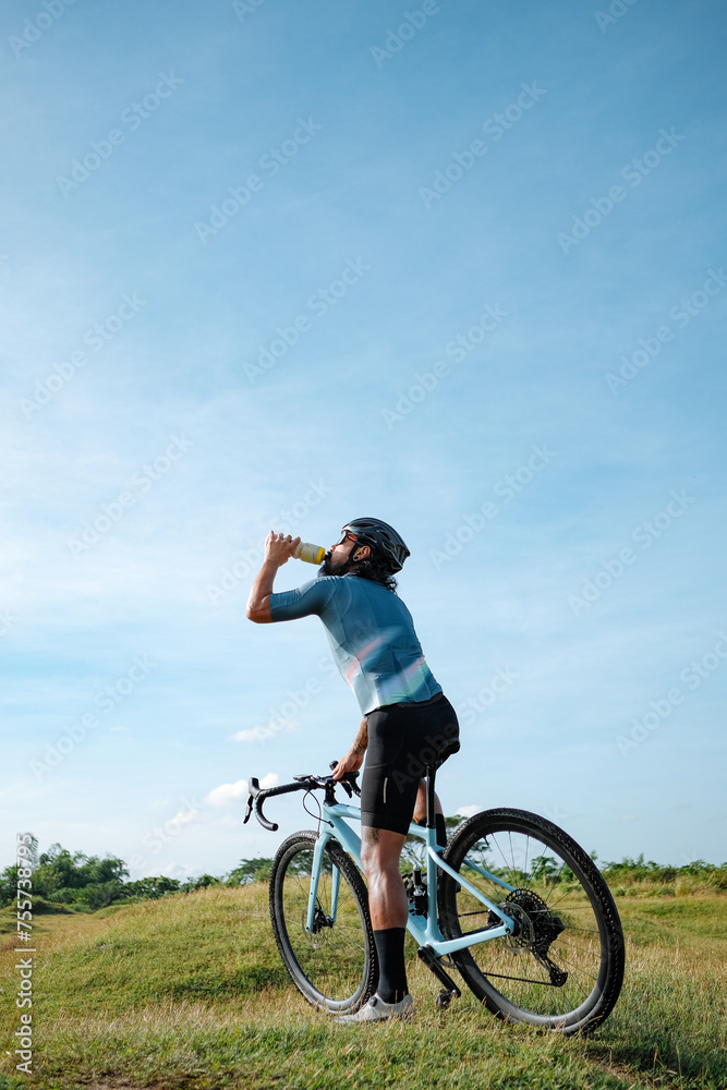 A middle age man drinking water in his gravel bike. A middle age man drinking water in his gravel bike.