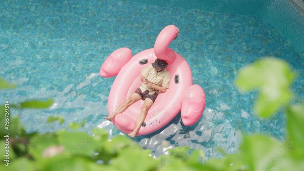 Young man Relaxing on a Pink Flamingo Float in a Pool During Summer