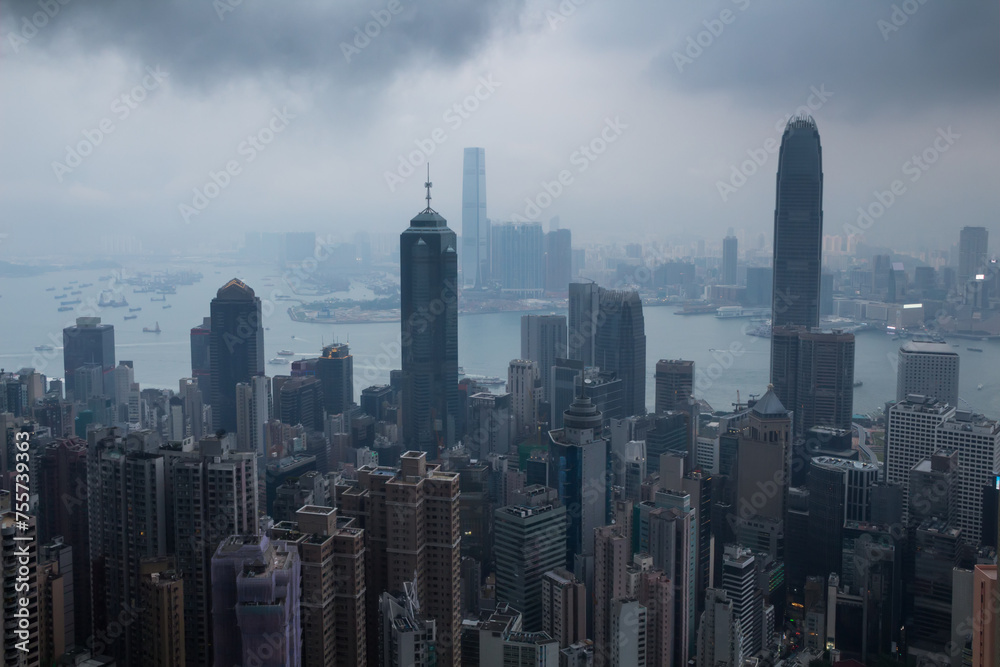 Skyscrapers, sea shore with ships, dark clouds in business area in mist in Hong Kong, China, view from Queen Garden
