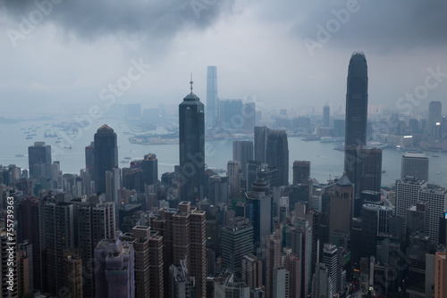 Skyscrapers, sea shore with ships, dark clouds in business area in mist in Hong Kong, China, view from Queen Garden