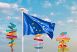 Waving flag of the European Union with colorful wooden direction signs