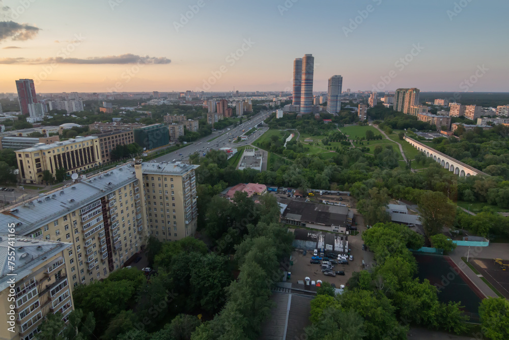 Road, green park and skyscrapers in Moscow, Russia at summer evening