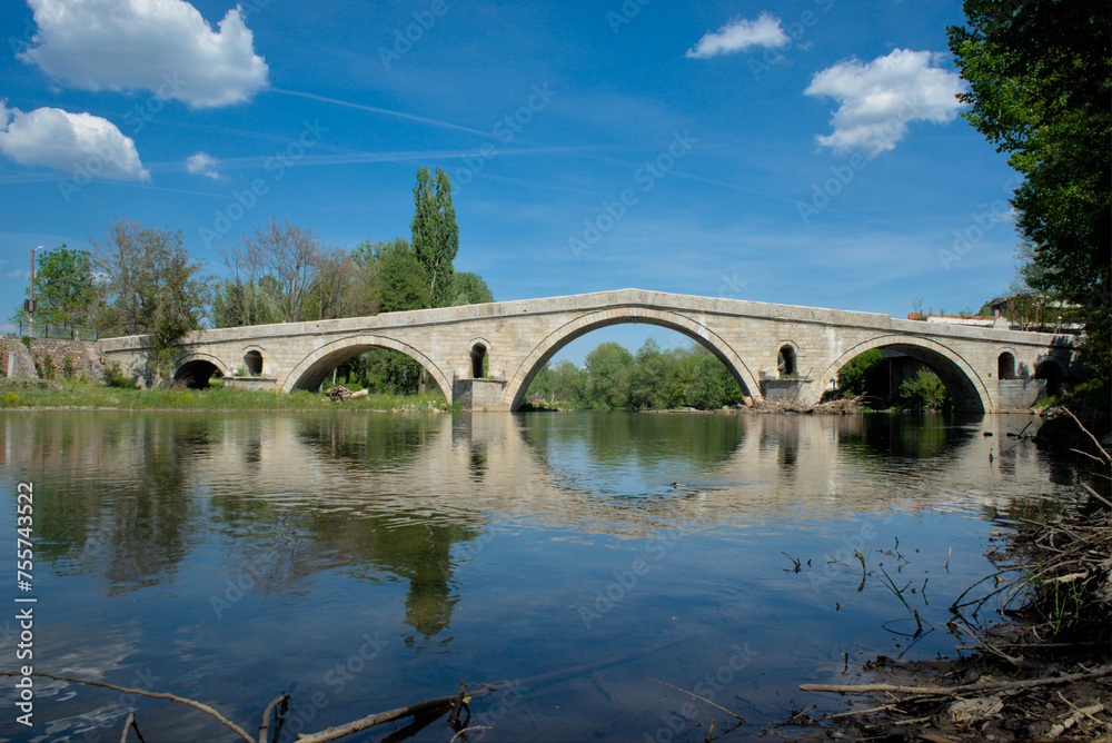 The ancient Roman bridge over a river in Bulgaria, featuring beautiful symmetrical arches reflected in the water