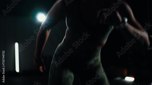 Close up shot - Sportswoman doing side lunges in the gym in a fast pace. Dark background and mood lightening