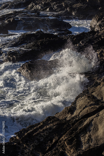 The ocean waves are crashing against the rocks, creating a powerful