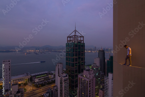 Man stands on edge of balcony of  Hotel and looks down in Hong Kong, China