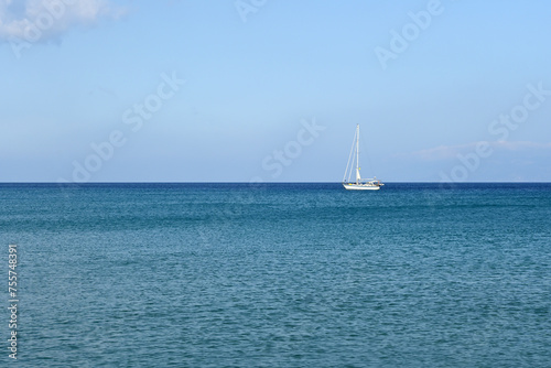 A lonely sailboat against the background of the turquoise Aegean Sea. Greece