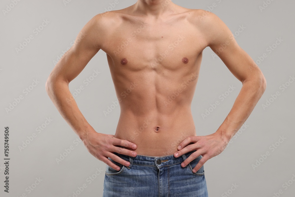 Shirtless man with slim body on grey background, closeup