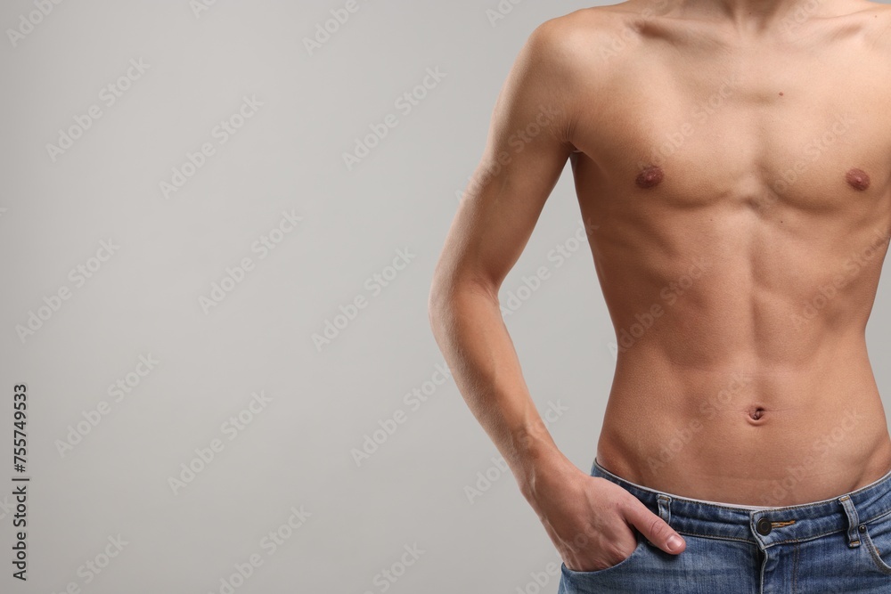Shirtless man with slim body on grey background, closeup. Space for text