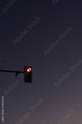 A red traffic light against the hues of a violet sunset sky