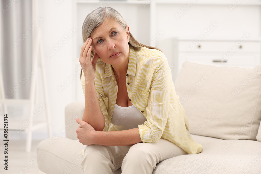 Menopause. Woman suffering from headache on sofa at home Menopause. Woman suffering from headache on sofa at home