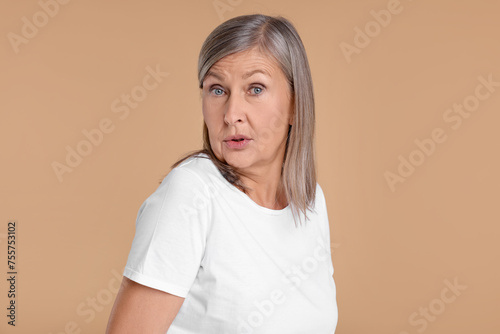 Portrait of surprised senior woman on beige background © New Africa