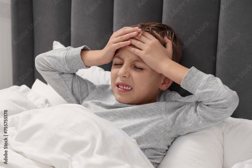 Little boy suffering from headache in bed at home Little boy suffering from headache in bed at home