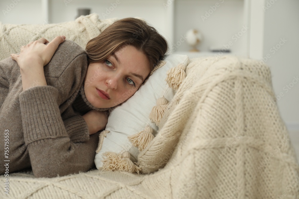 Sad young woman lying on sofa at home, space for text Sad young woman lying on sofa at home, space for text