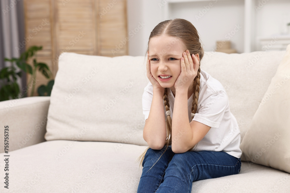 Little girl suffering from headache on sofa indoors. Space for text Little girl suffering from headache on sofa indoors. Space for text