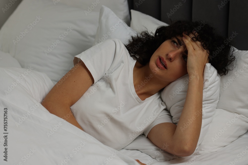 Young woman suffering from headache in bed at night Young woman suffering from headache in bed at night