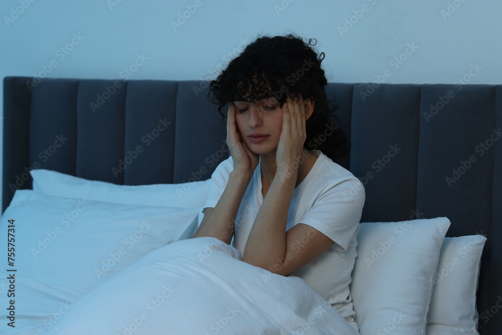 Young woman suffering from headache in bed at night Young woman suffering from headache in bed at night
